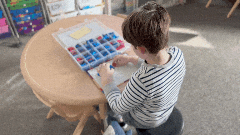 GIF of little boy sitting at a table stimming while he plays a learning game