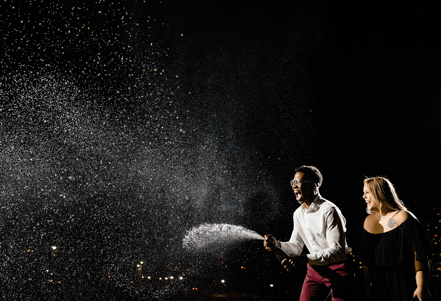 diverse-couple-sprays-champagne-at-their-downtown-austin-engagement-photo-session