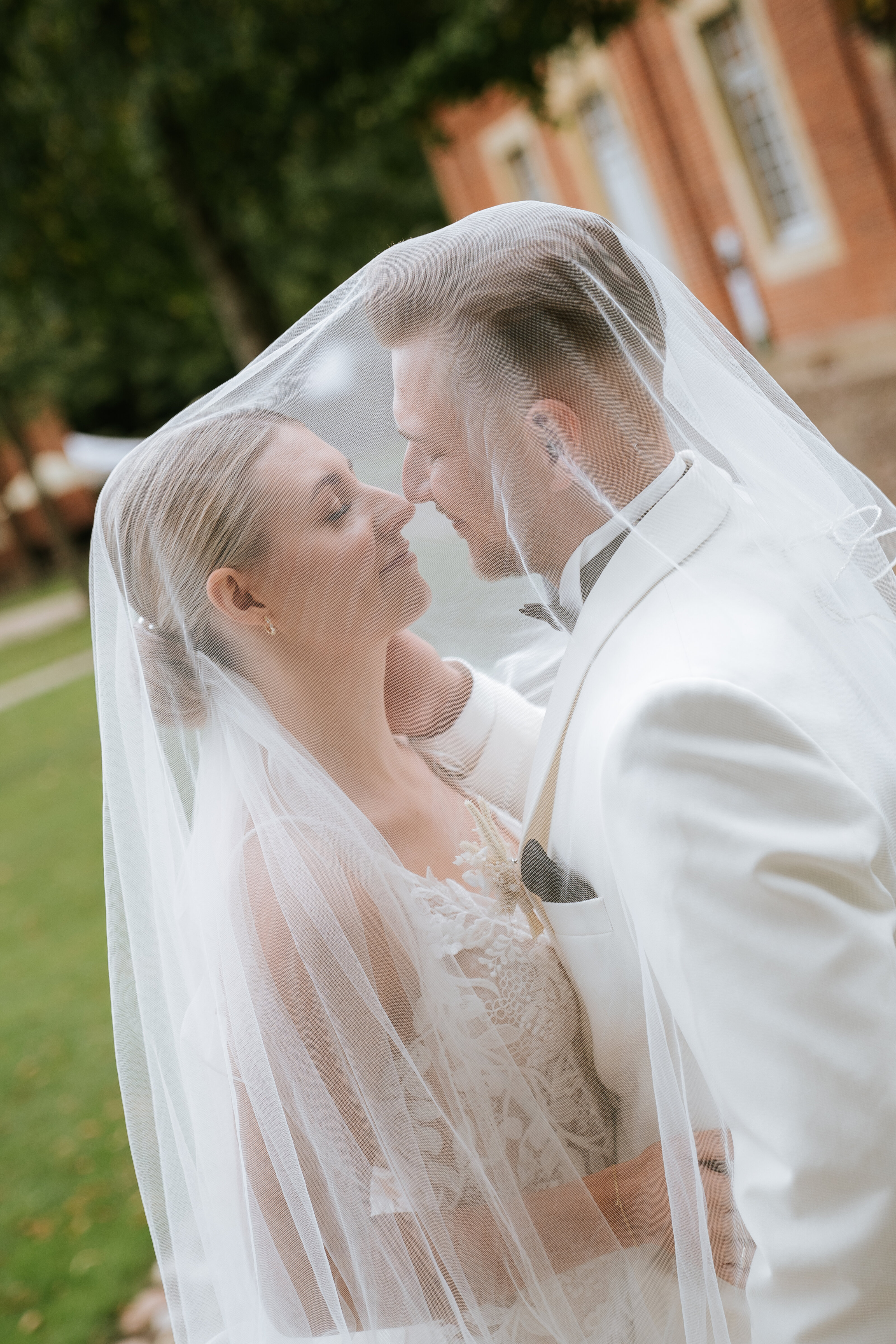 Bräutigam im hellblauen Anzug mit Ansteckblume vor rustikalem Fachwerk; ruhiges Porträt für natürliche hochzeitsfotografie, klassische hochzeitsfotos und professioneller fotograf hochzeit