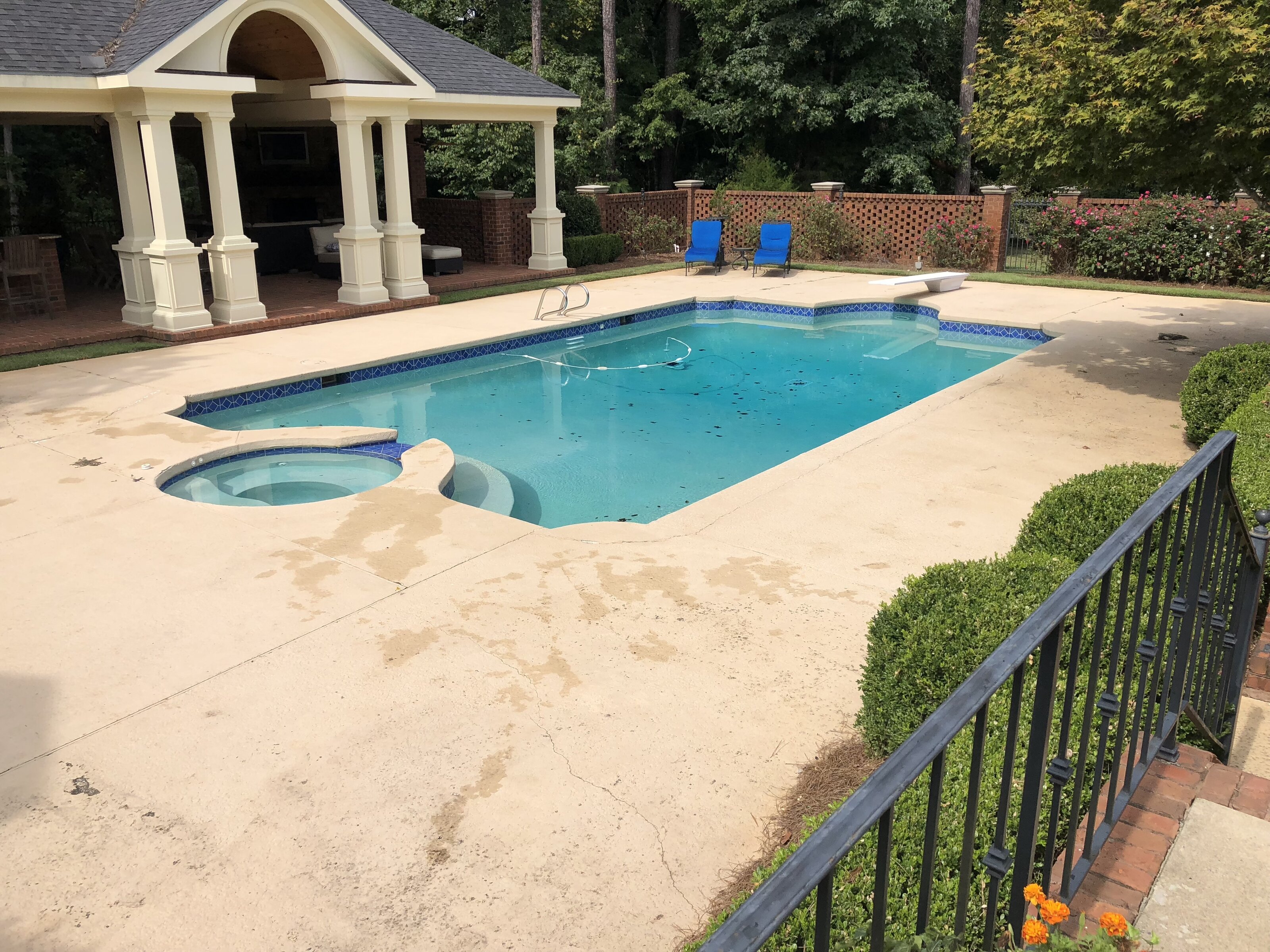 Inground pool before renovation — dated stamped concrete deck and raised stone spa in Middle Georgia