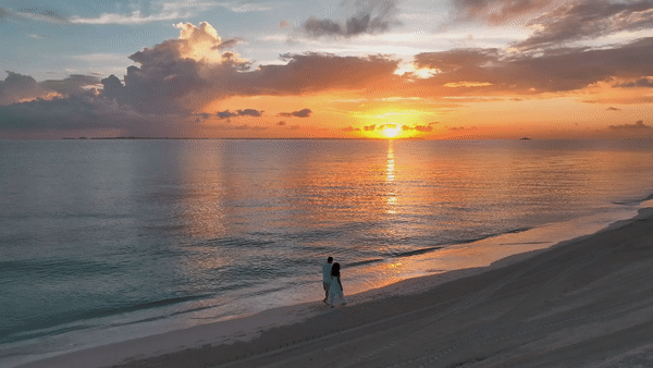 Couple walks along the beach at sunset