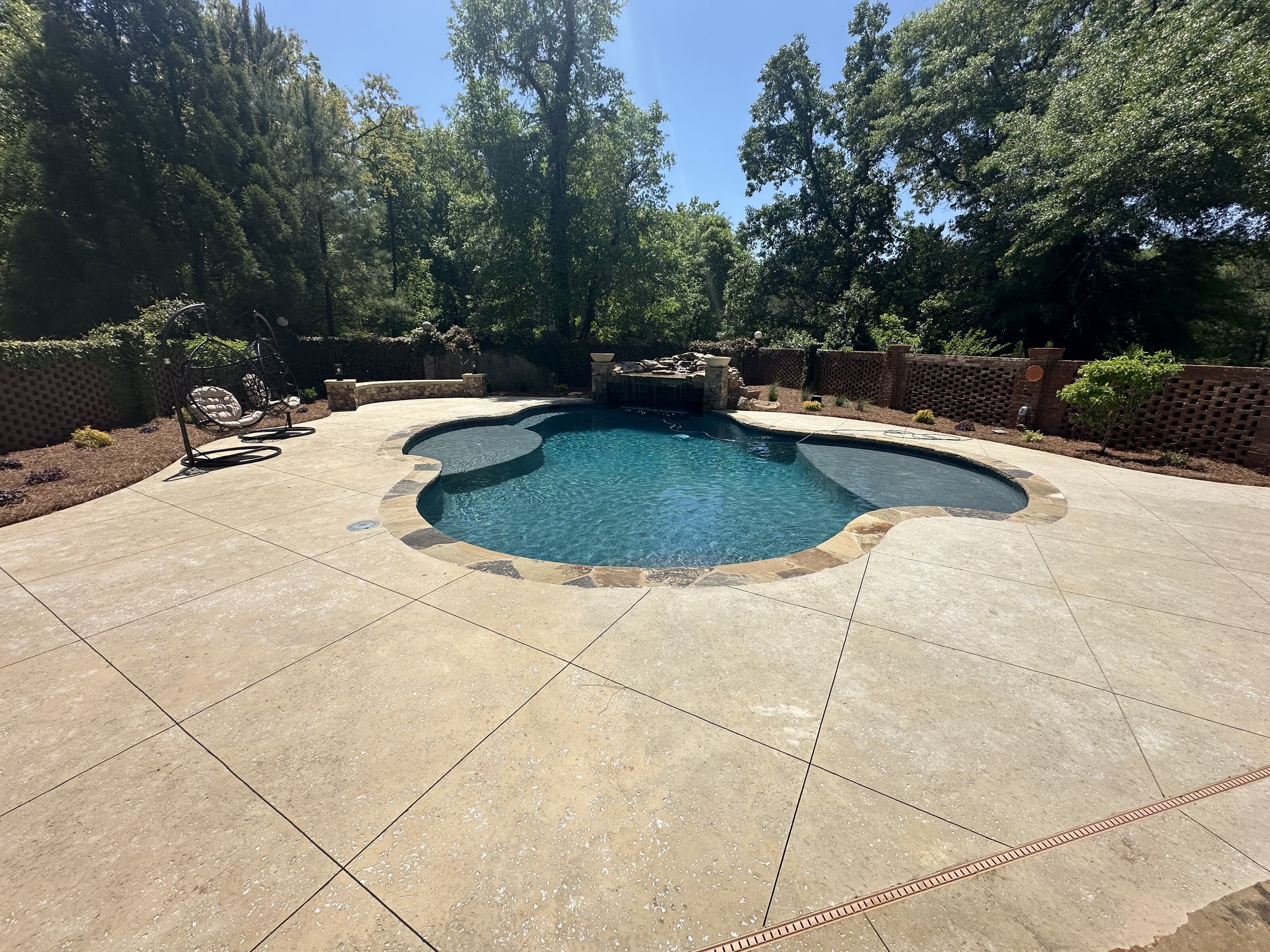 Pool renovations near Warner Robins — freeform pool with waterfall, new stamped deck, and landscaping by Mid State Pools