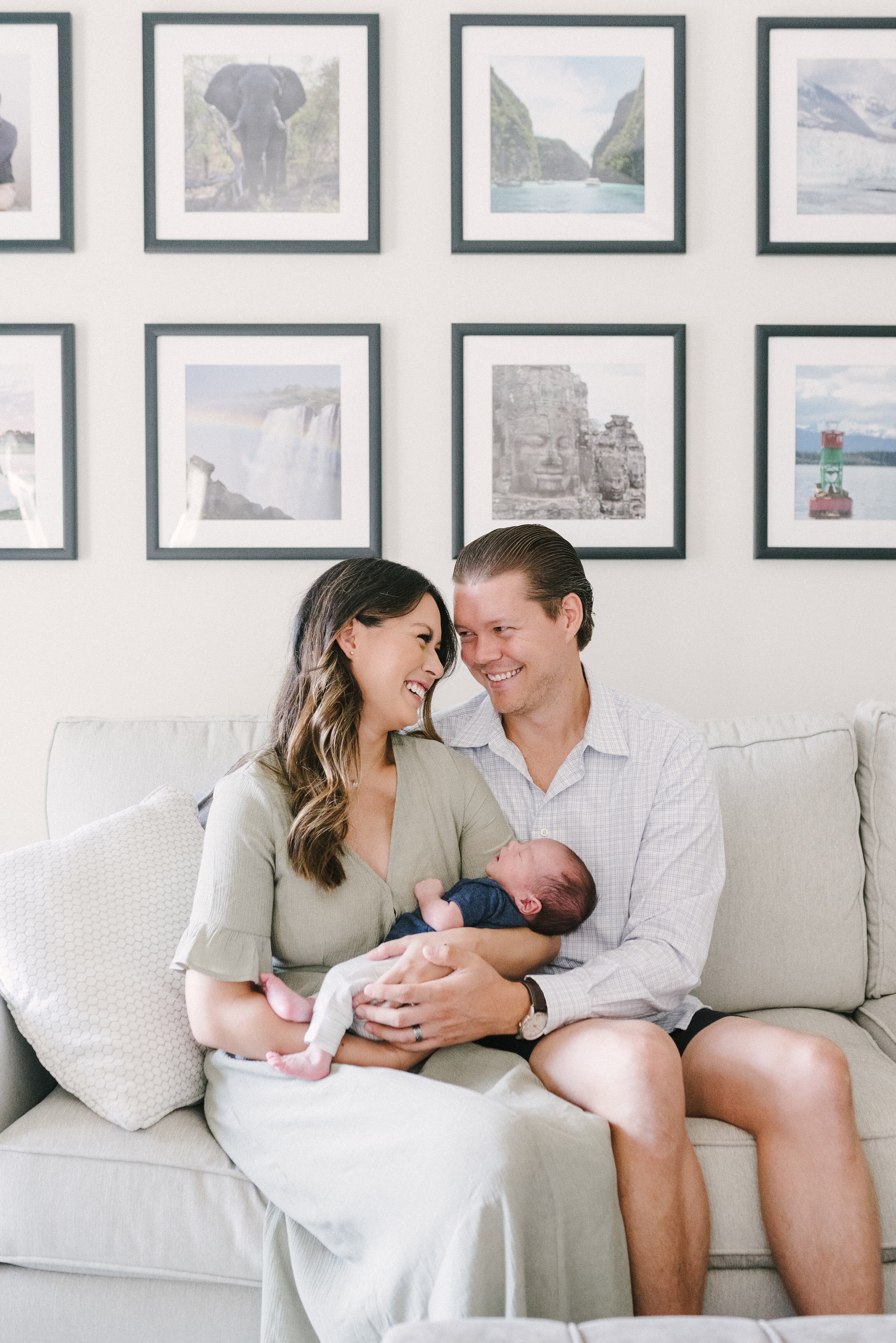 Nashville Newborn Photography Session at a client home with Nashville Newborn Photographer Dolly DeLong Photography A Photo Of A Mom Holding Her Newborn Baby On The Couch With Dad And Smiling