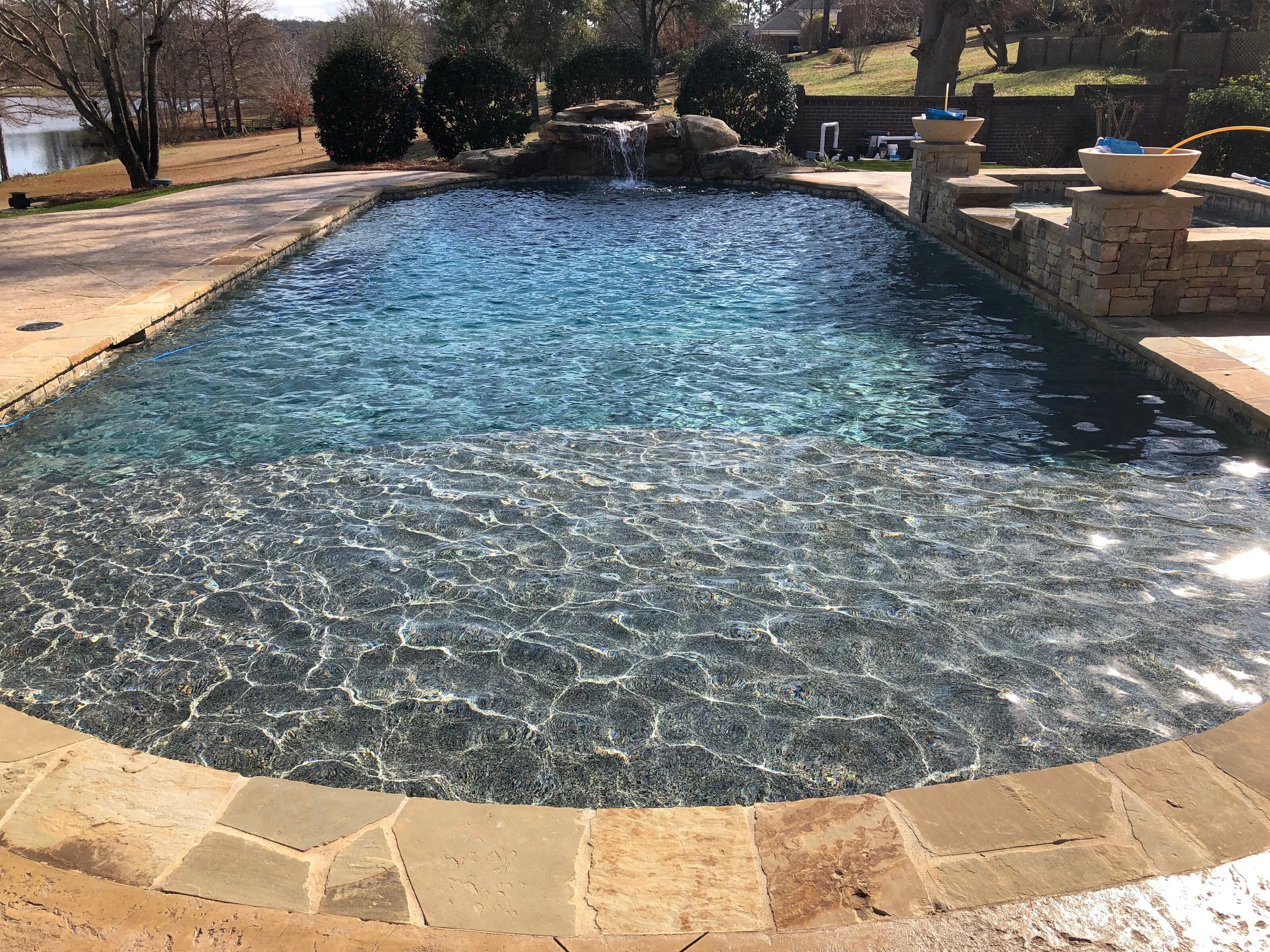 Best pool renovation company near Warner Robins — crystal clear pool with boulder waterfall and fire bowls by Mid State Pools