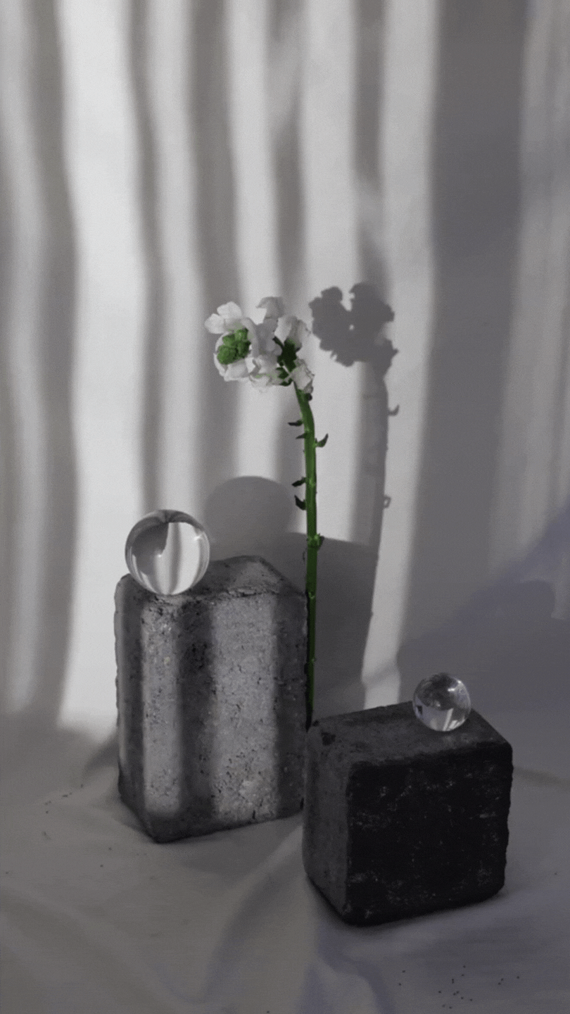 A white orchid flower next to a crystal ball on a cement stand.