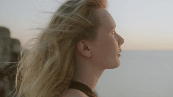 GIF: Frau auf einer Klippe über der ruhigen See, der Wind weht in ihrem Haar, der Blick auf den Horizont gerichtet – befreiende Perspektiven und Selbstreflexion