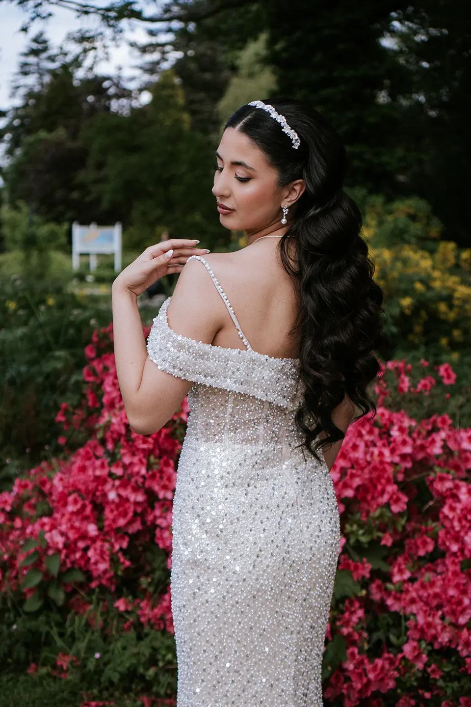 Elegantes Solo der Braut: schimmerndes Kleid, offene Rückenlinie und Wellenhaar vor pinken Blüten; fine art hochzeitsfotografie und hochzeitsfotografie mit stil
