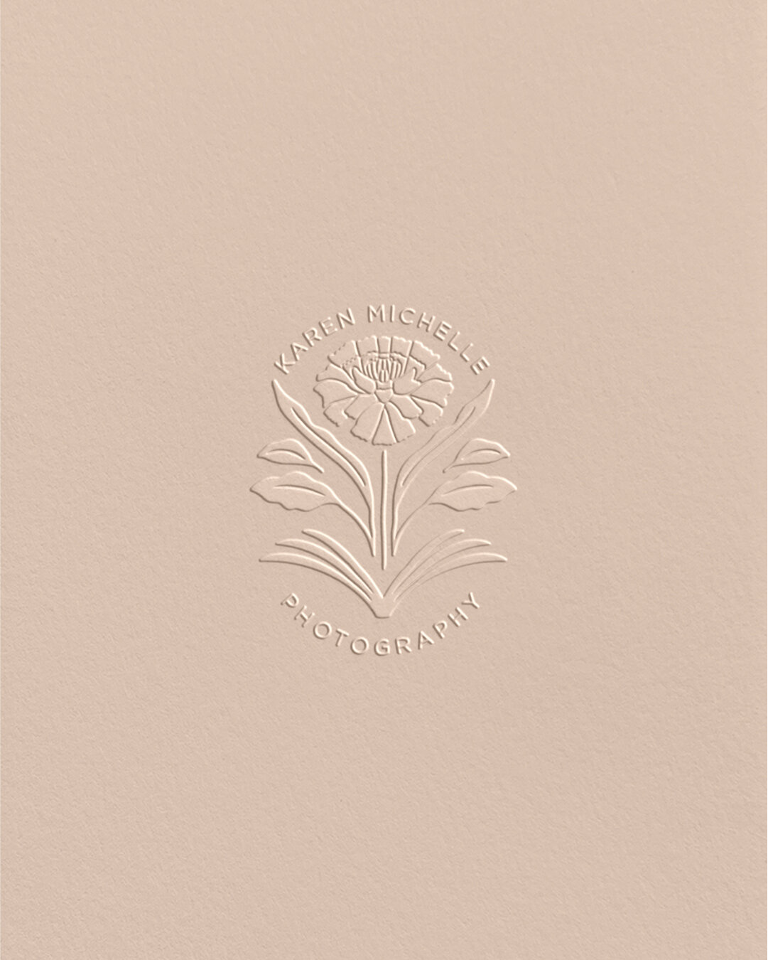 Close-up of embossed Karen Michelle Photography emblem—marigold symbol representing memory and heritage.