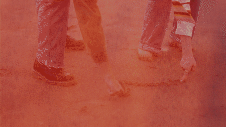 couple drawing heart in the sand