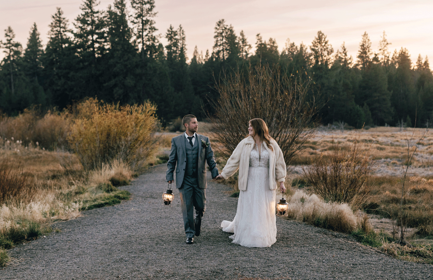 A bride & groom carry lanterns and walk the Deschutes River Trail near Dillon Falls in Bend, Oregon at dusk.