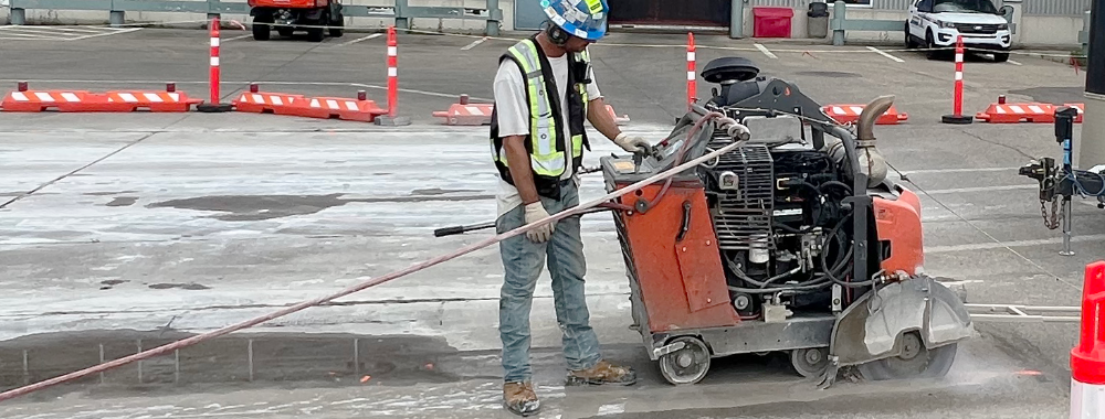 An operator using a concrete slab saw to cut through concrete