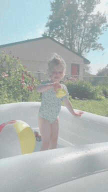 gif of young siblings playing in large inflatable pool in the backyard