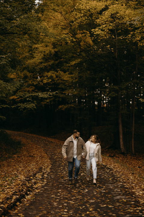 GIF of New England couple running down tree lined road