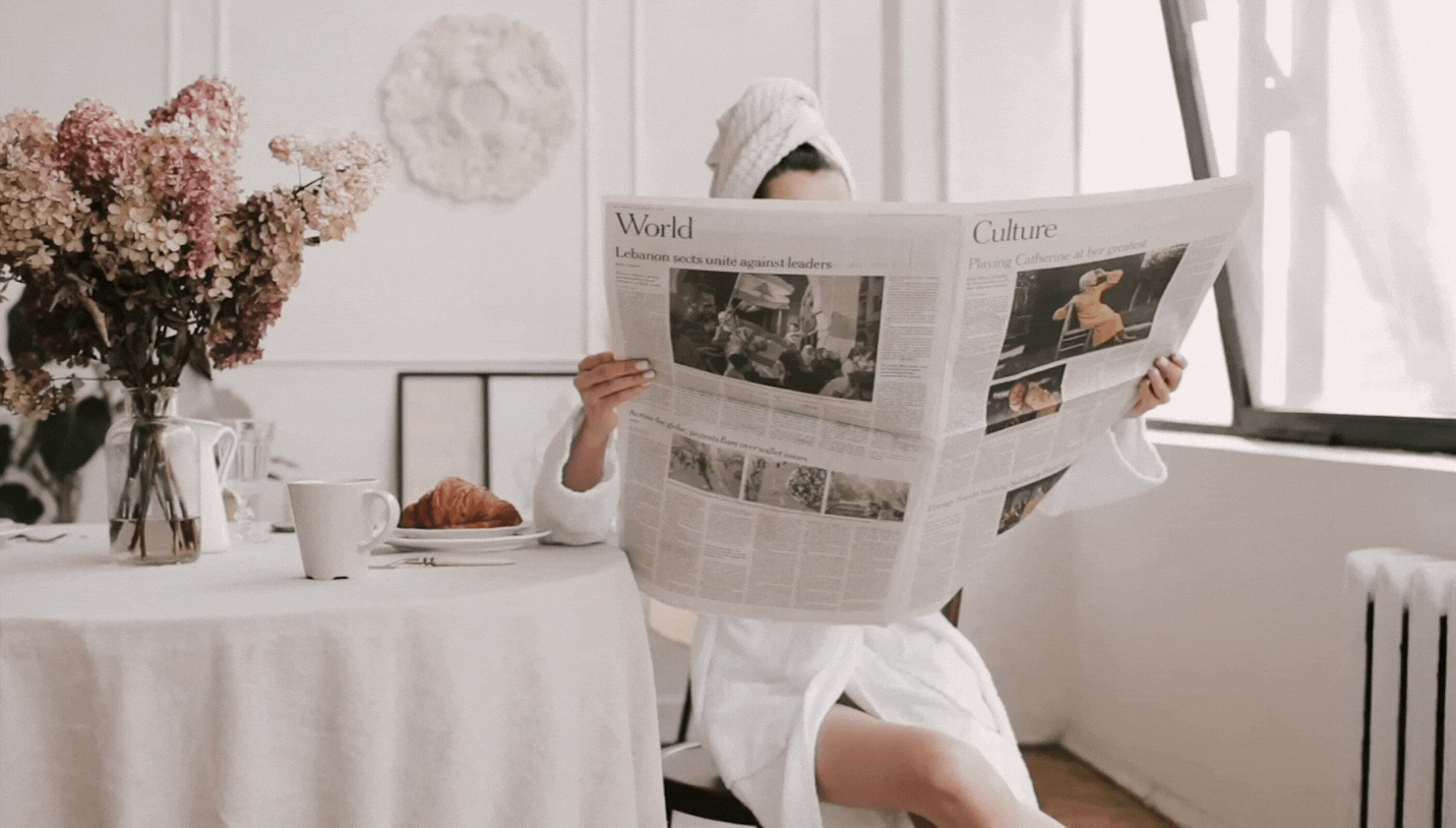 Background video of girl  sitting next to breakfast table closing newspaper