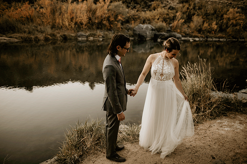 bride twirling dress holding husbands hand by a river