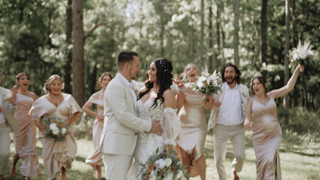 wedding party surrounding bride and groom while laughing and smiling