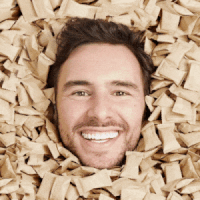 Headshot of man surrounded by soap products smiling then mouth open smiling.