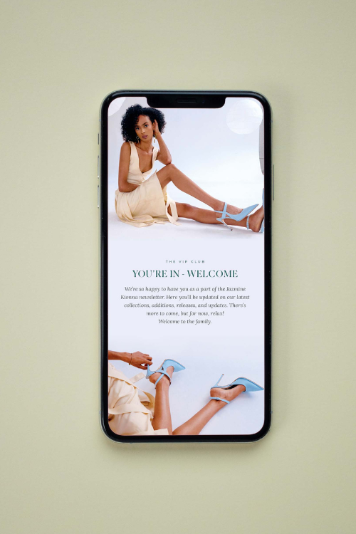 iPhone on green background with woman wearing blue shoes on top of words that say you're in - welcome