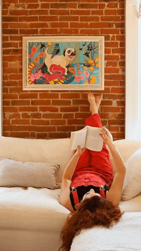 A GIF of a woman laying on a couch with her feet up reading a book.