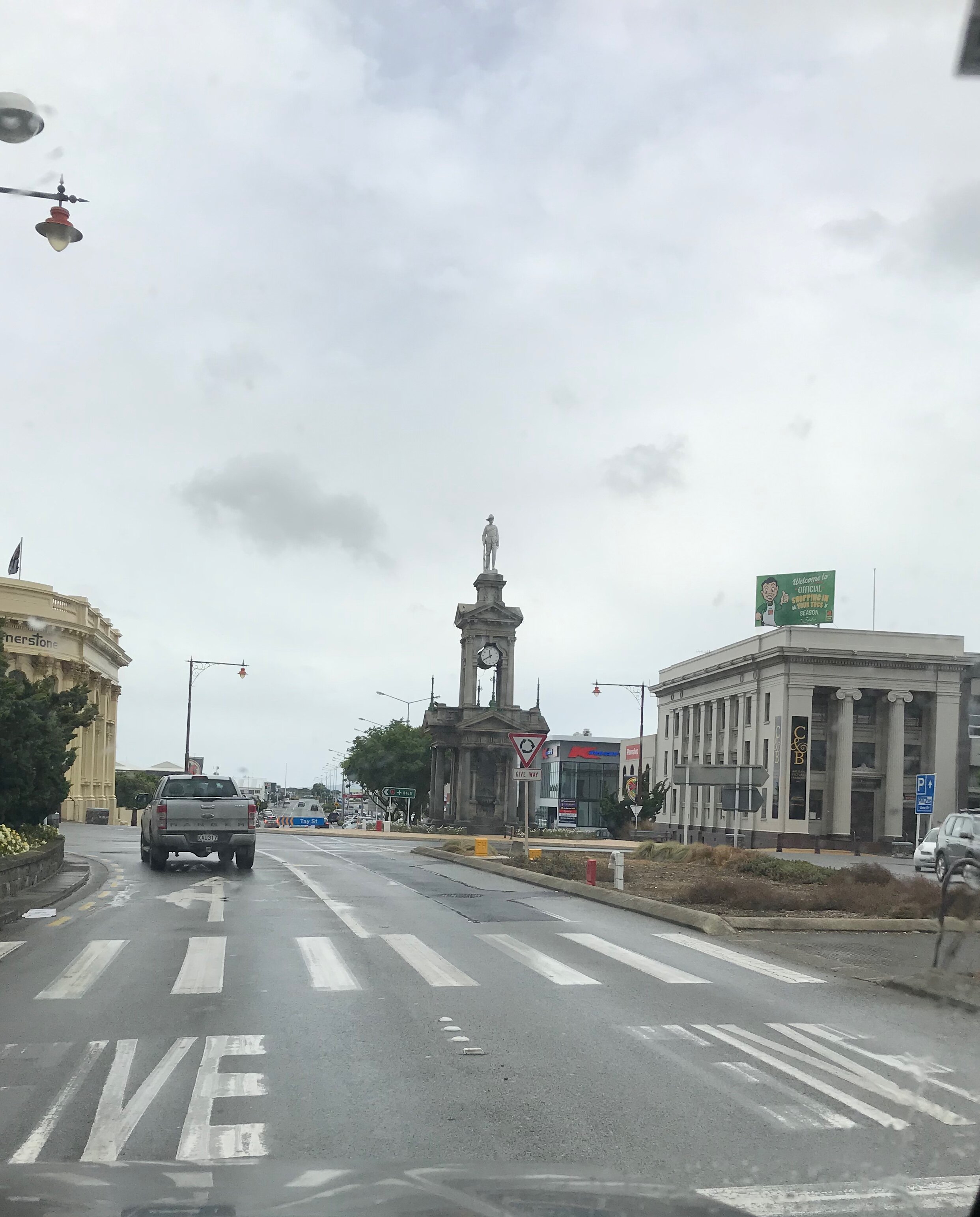 Wide streets of Invercargill showing the Cenotaph monument at the Dee and Tay Street roundabout on a grey day.