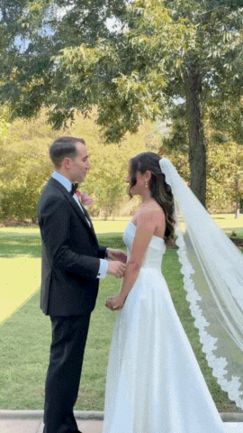 GIF of a bride and groom hugging and posing outside of a building 
