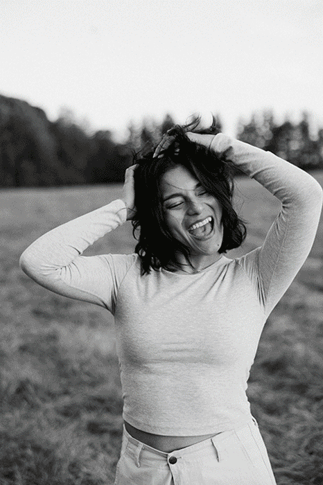 Portraits of a fun adventurous wedding photographer in New York in a field at golden hour laughing