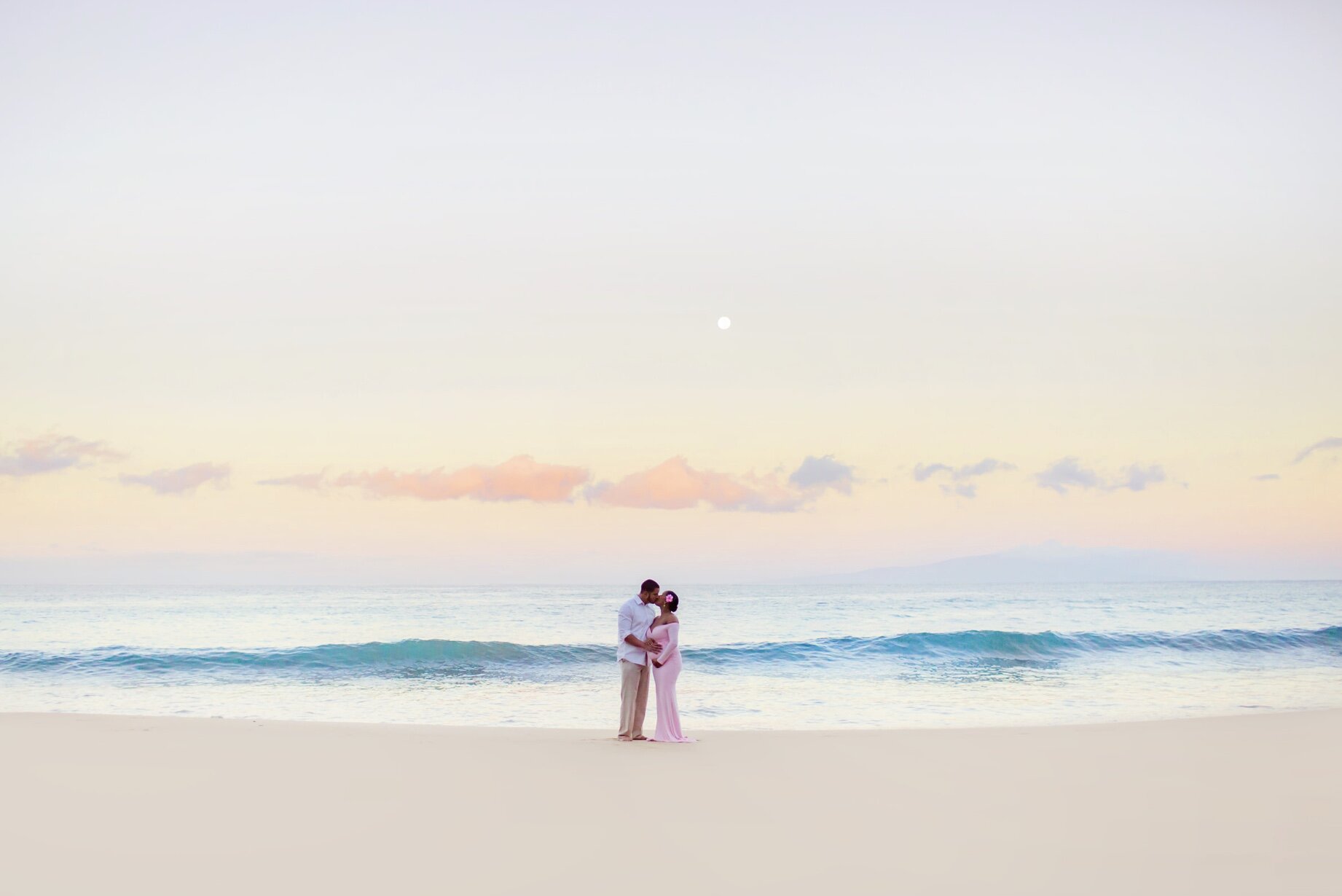 wide photo of pregnant woman in pink maternity gown at sunrise in hawaii by love andwater