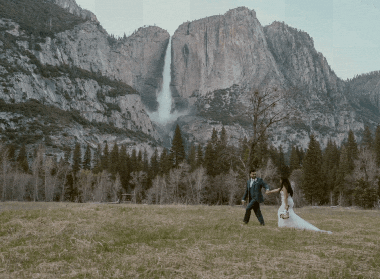 bride and groom walking with yosemite falls in background
