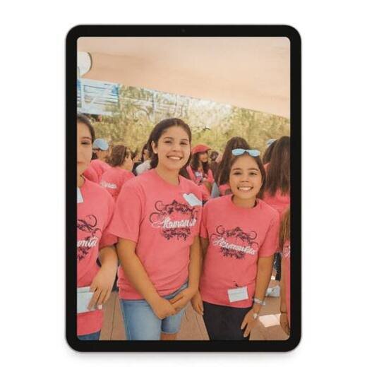 Young Latinas sponsored through the Hermanitas MANA program, smiling together in pink t-shirts at a community education event