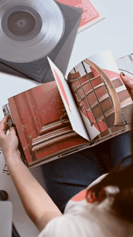 GIF of hands flipping through a coffee table book of images