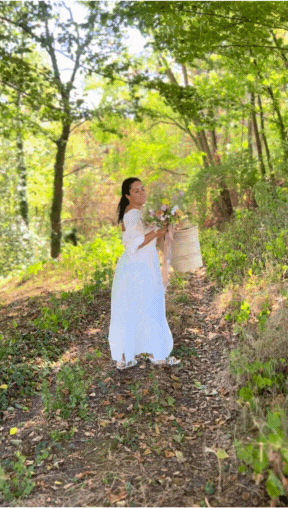 Natalia treads among a forest picking flowers.