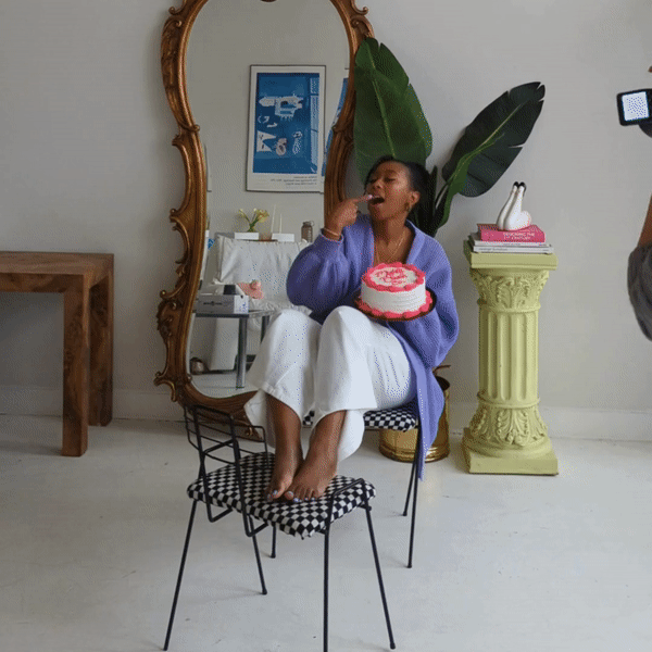 A gif of a woman sitting on a chair and eating cake