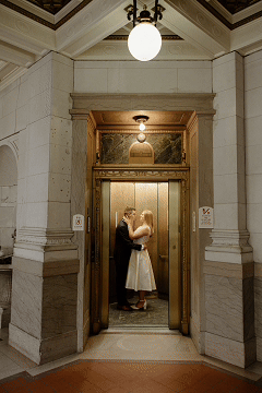 couple kissing while elevator doors close in front of them during their Hartford City Hall Engagement session