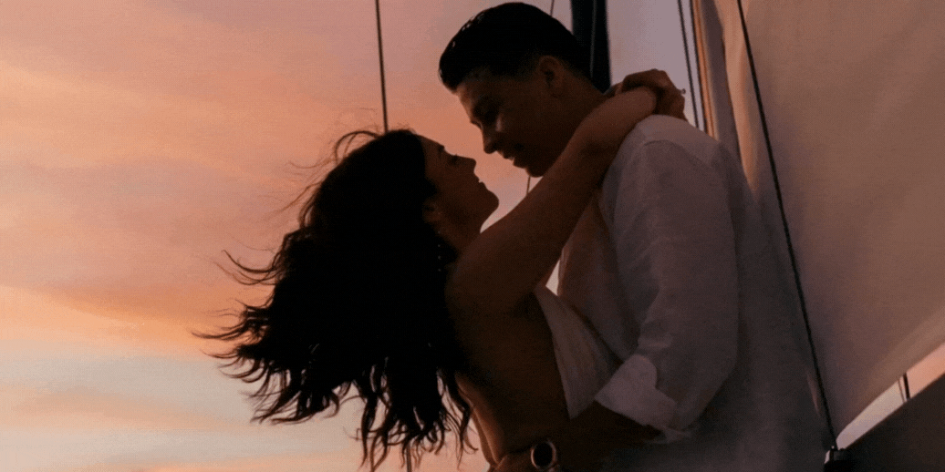 Cinematic couple kissing while sailing at sunset during romantic elopement, West Coast destination wedding photographer