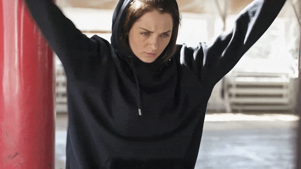 White woman wearing a black hoodie warming up for a workout