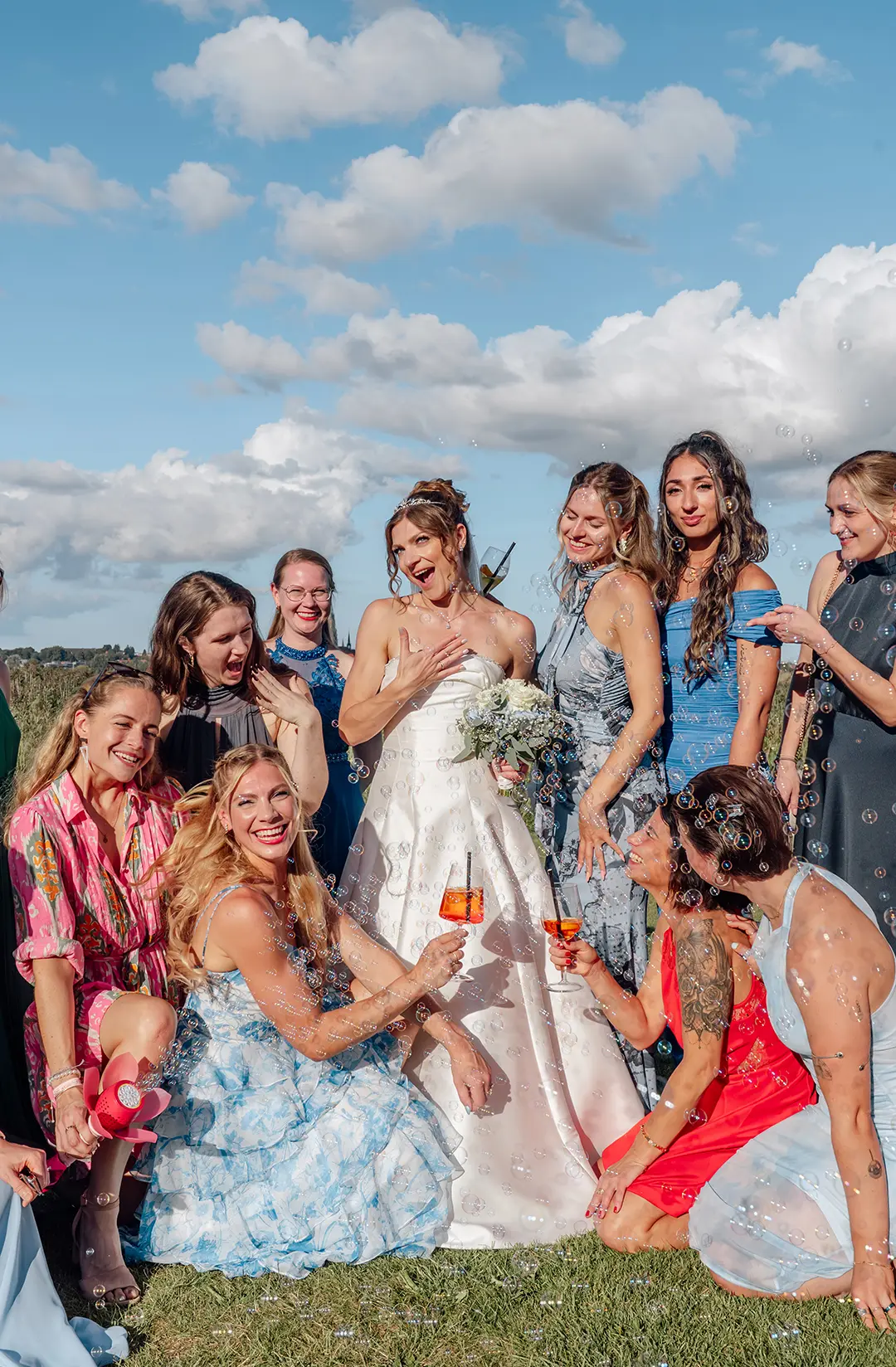 Hochzeitsfotos Schleswig-Holstein – fröhliches Gruppenfoto der Braut mit ihren Freundinnen und Sektgläsern am Strand.