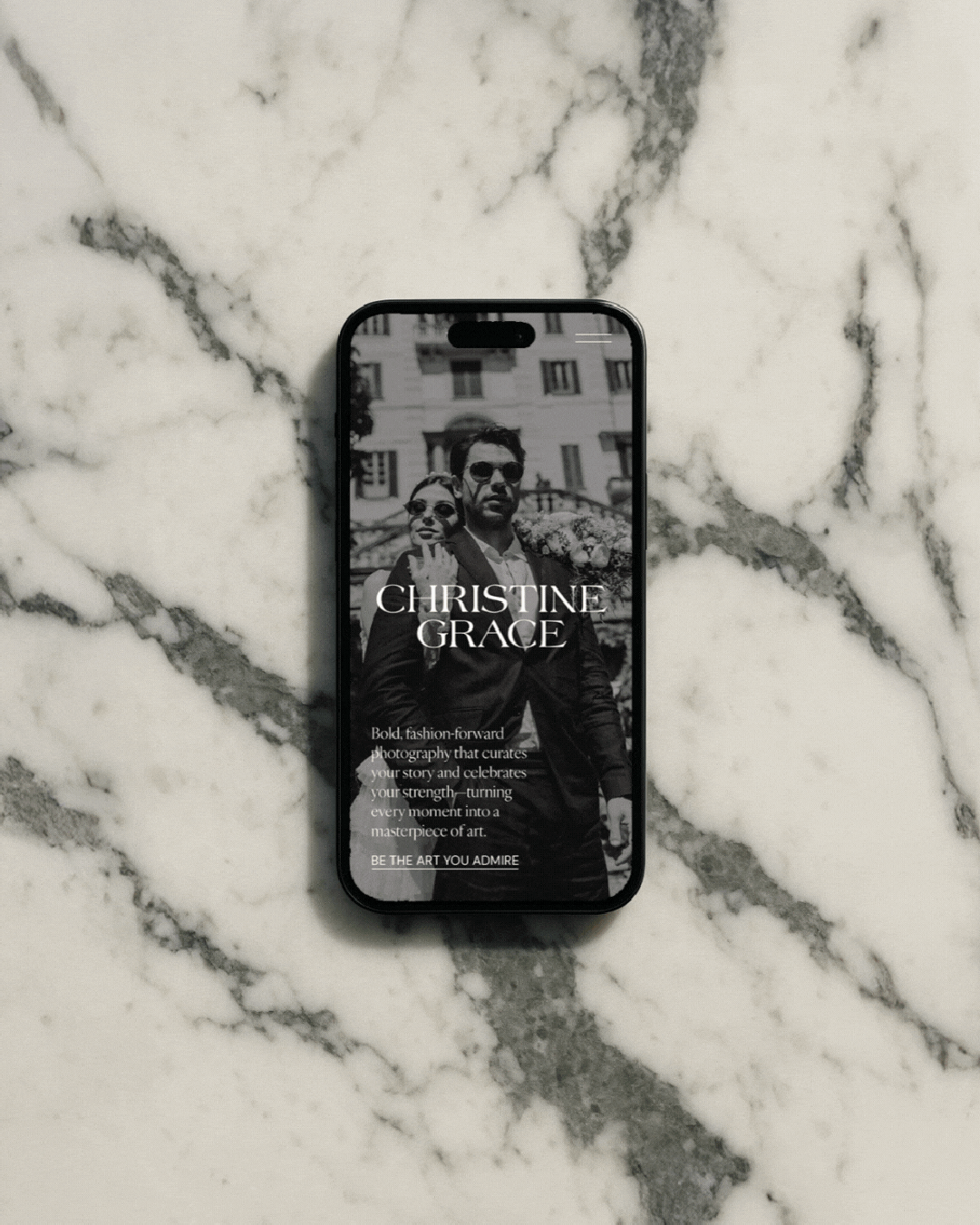 Marble flatlay featuring an iPhone website design mockup with a black-and-white couple portrait and the Christine Grace logo.
