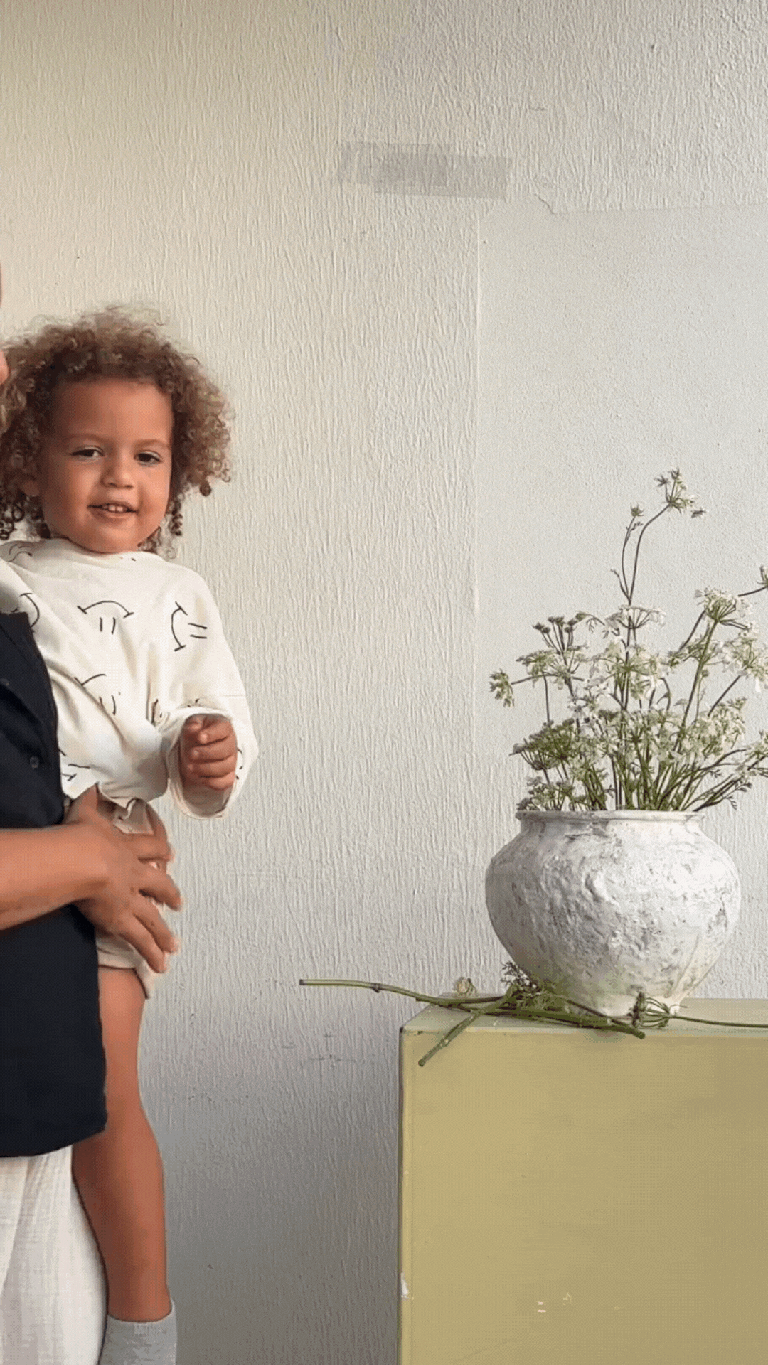 Kai, Natalias son, is being carried by her and they wave toward the camera.