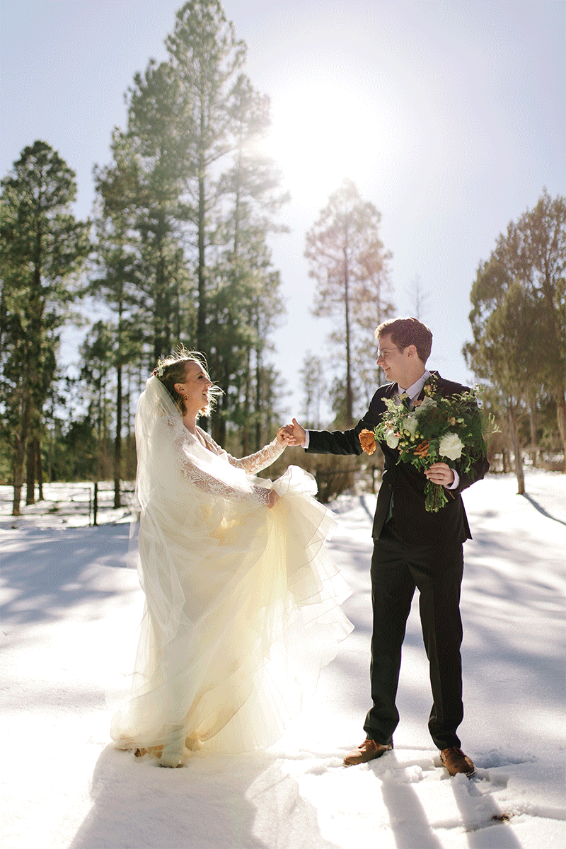 couple in wedding attire twirling in snow in show low arizona