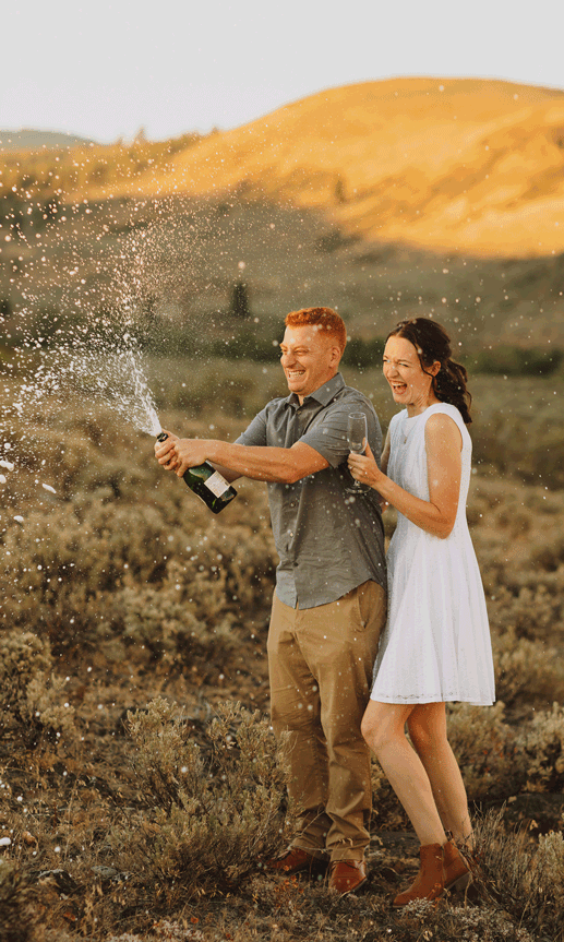 Couple celebrating engagement with champagne spray