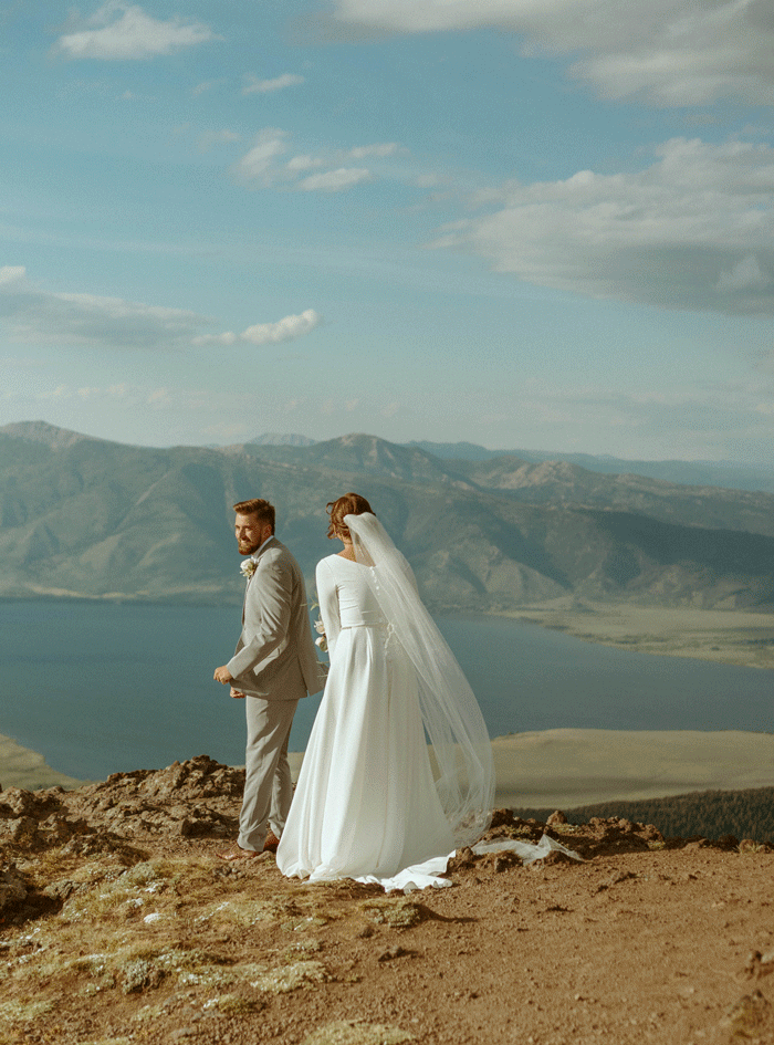 the perfect first look moment between bride and groom in island park idaho on a cliff overlooking henrys lake
