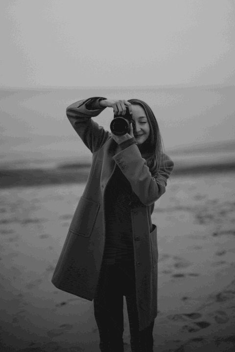 A GIF of a photographer taking a photo and then putting down her camera and smiling.