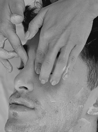 Video of a male laying down getting a lymphatic massage on his face, head and shoulders