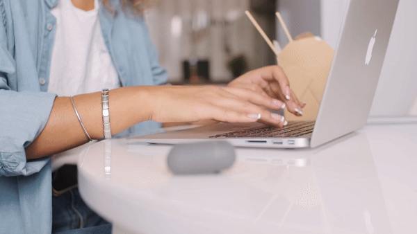 woman typing on a laptop next to a take out box