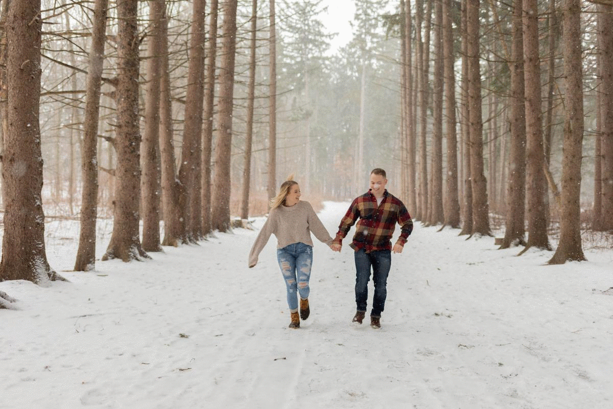 man and woman skipping through snow