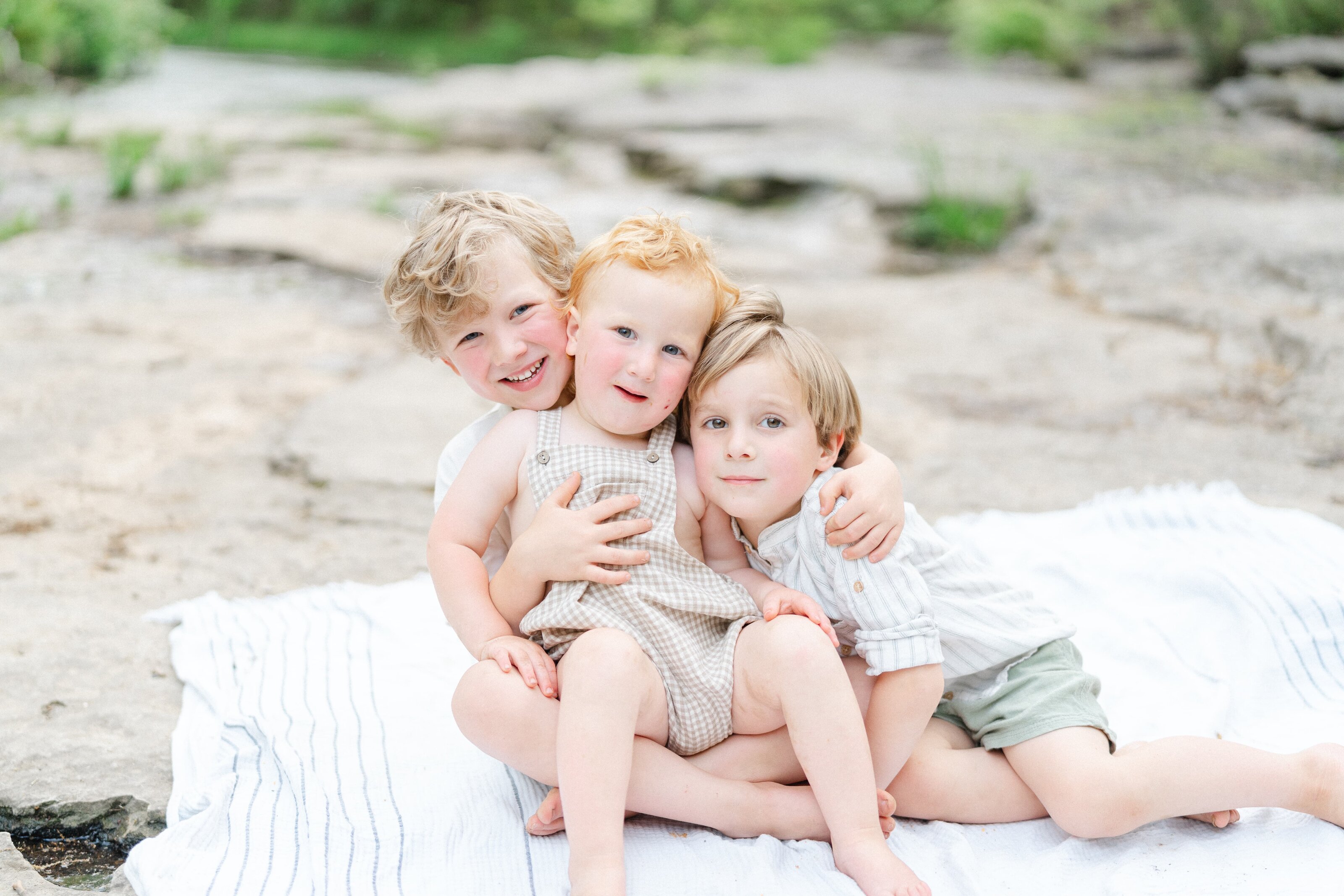 Three Brothers Are Sitting On A Picnic Blanket At The Nashville Ag Center For Family Photos And Are Smiling For The Camera by Nashville Family Photographer Dolly DeLong Photography