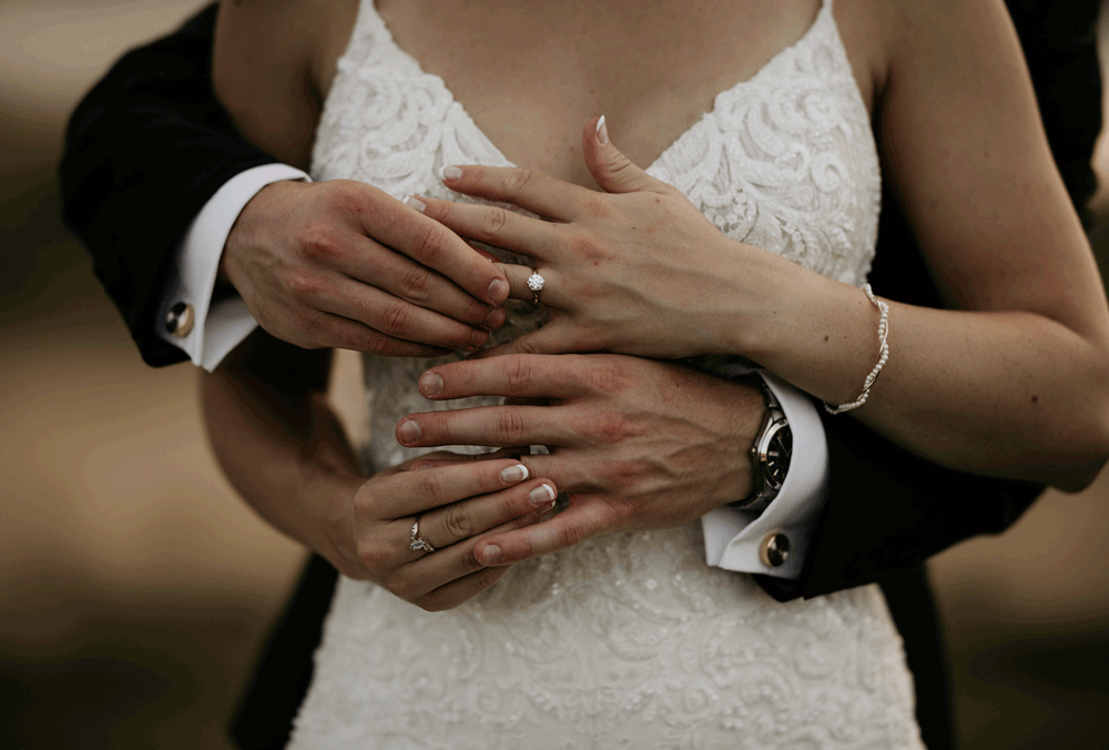 Man and woman place wedding rings on fingers during mountaintop microwedding.
