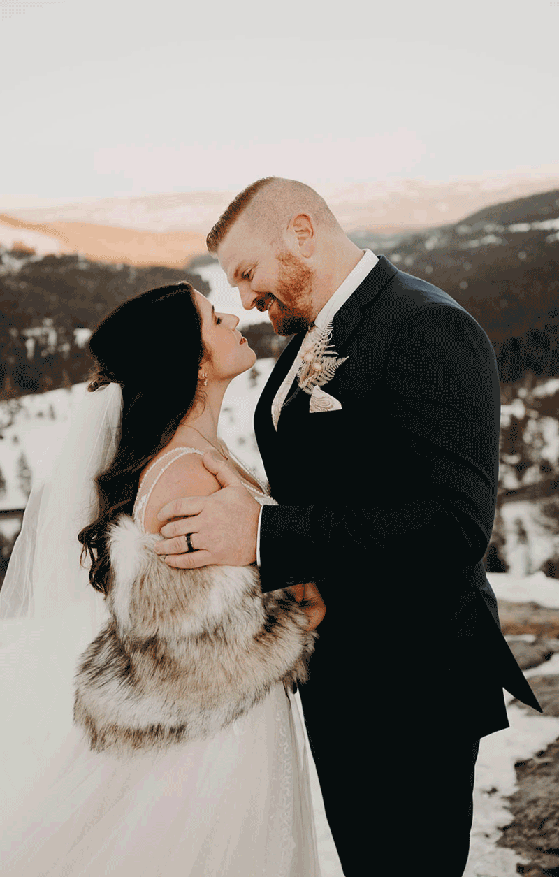 moving GIF of a groom kissing his bride with a mountain view behind