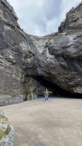 A GIF of Danielle Rose Photography, a travel elopement photographer, spinning in a circle at Hug Point Falls, Oregon, capturing the joy and excitement of working amidst the stunning natural beauty of the waterfall and coastline.