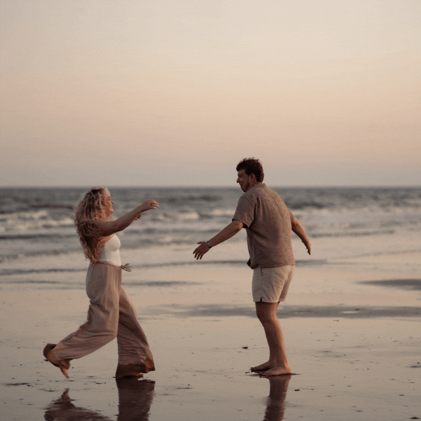 Couple running into each other at the beach and the guy swinging the girl around in a circle.